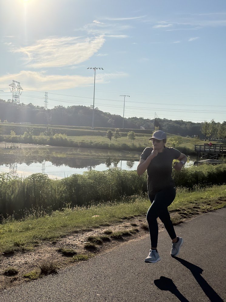 A runner on a path beside a still lake in early light