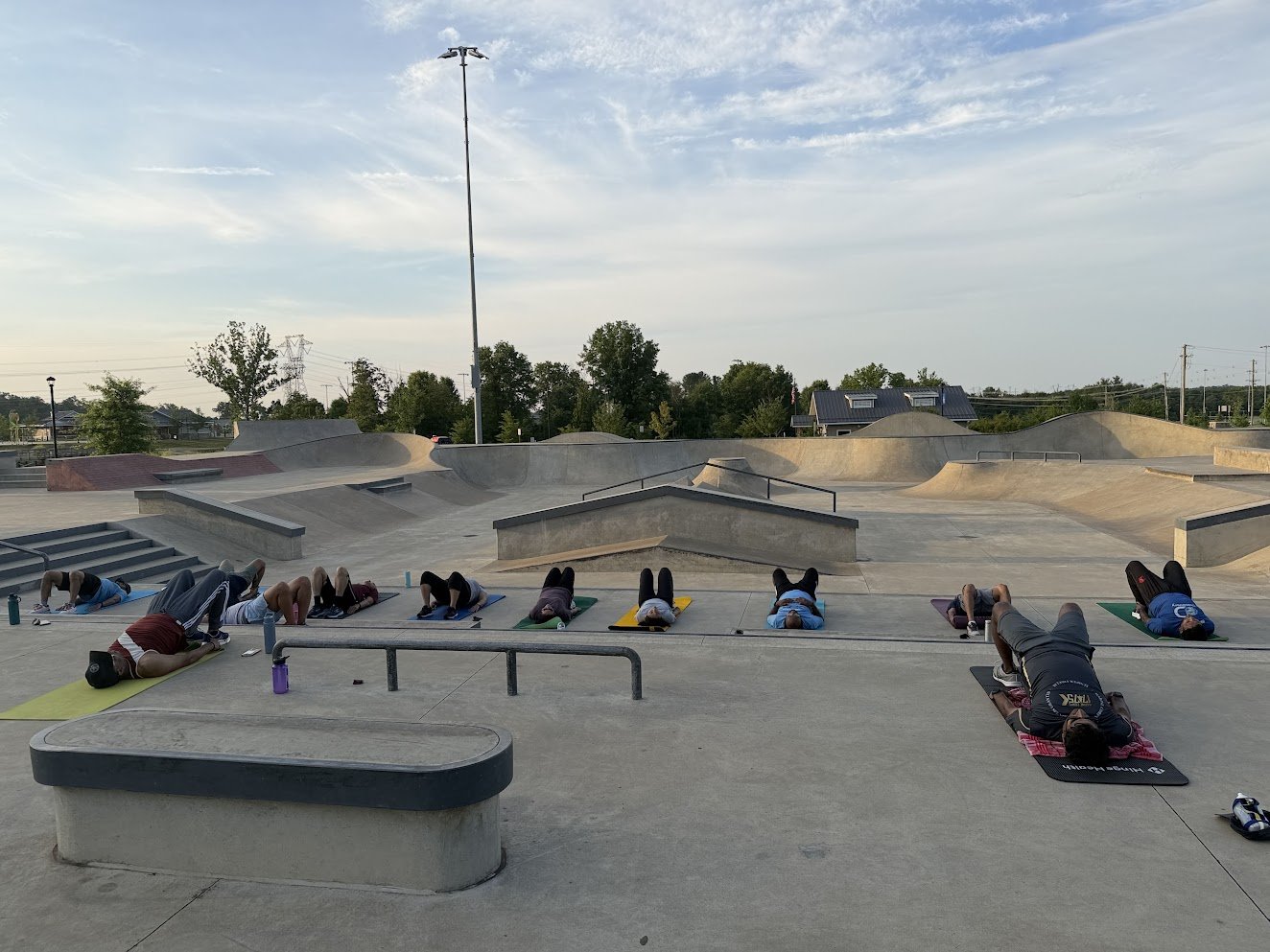 A yoga class on mats at an empty skatepark in the morning